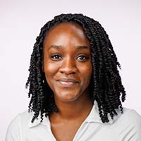 Photo of Mary Grace, a Black woman in a white shirt smiling at the camera